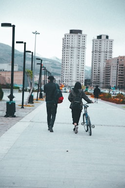 a man and woman walking down a sidewalk with a bicycle