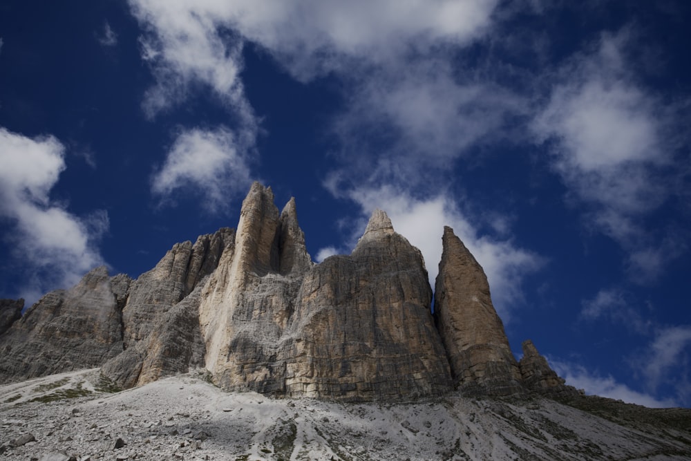 a rocky mountain with a blue sky with Tre Cime di Lavaredo in the background