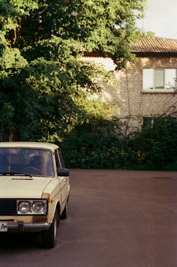 A well-kept older car parked on a quiet village street under soft daylight.