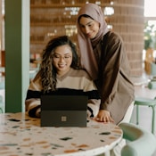 a woman and a girl looking at a laptop