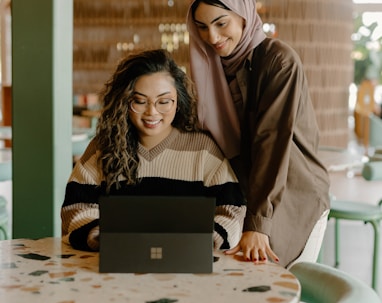 a woman and a girl looking at a laptop