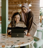 a woman and a girl looking at a laptop