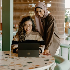 a woman and a girl looking at a laptop