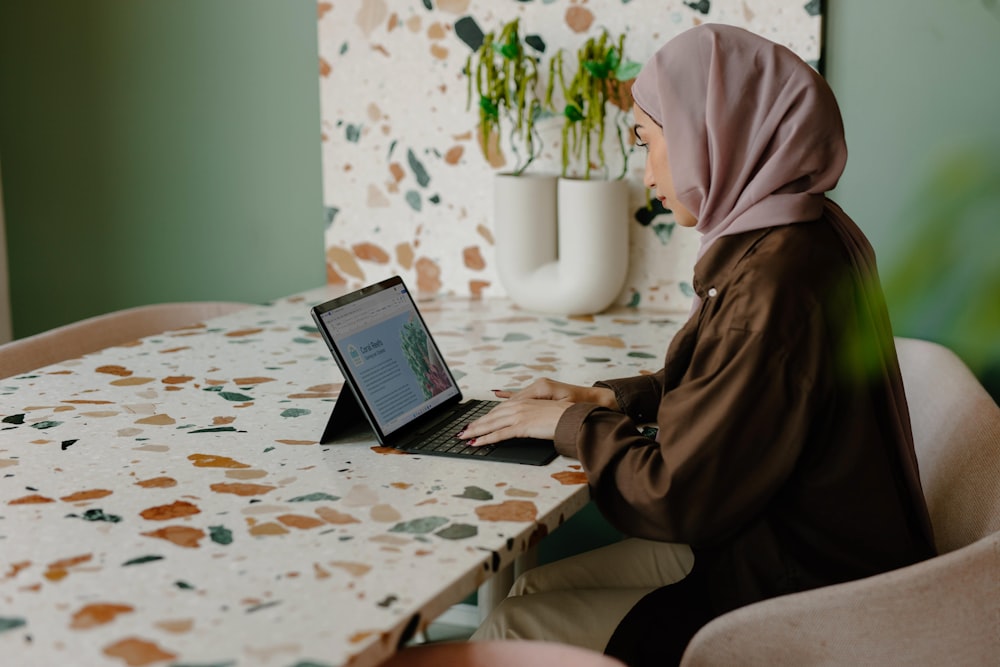 Eine Person, die mit einem Laptop an einem Tisch sitzt