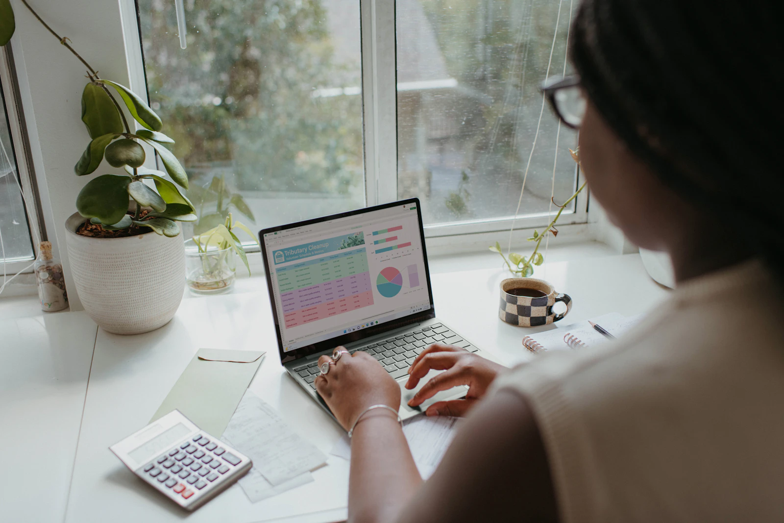 Person analyzing spreadsheet data with a laptop and calculator while comparing affiliate program economics