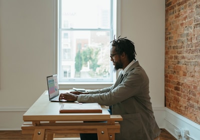 a person sitting at a desk with a laptop and papers