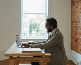 a person sitting at a desk with a laptop and papers