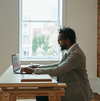 a person sitting at a desk with a laptop and papers