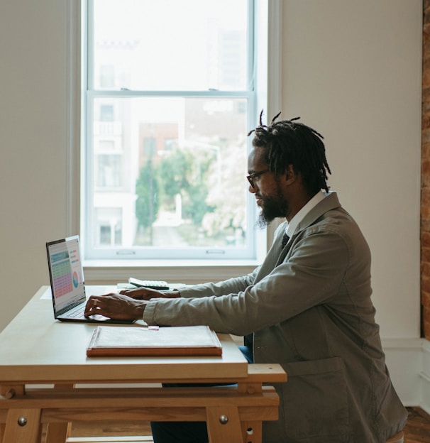 a person sitting at a desk with a laptop and papers