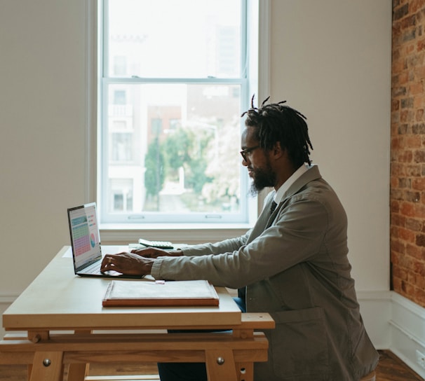 a person sitting at a desk with a laptop and papers