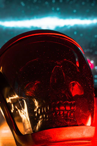 Close-up of a blood-red skull pendant glowing under dim lighting.