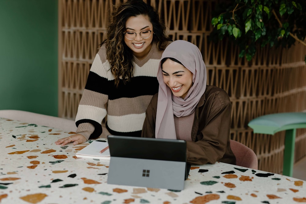 Duas mulheres sentadas em uma mesa com um laptop