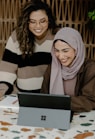 Two women sitting at a table with a laptop