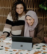 Two women sitting at a table with a laptop