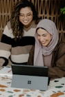 Two women sitting at a table with a laptop