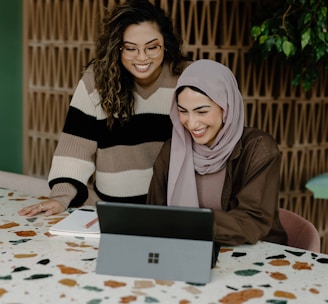 Two women sitting at a table with a laptop