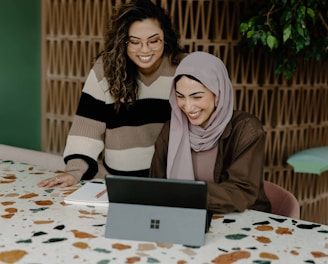 Two women sitting at a table with a laptop