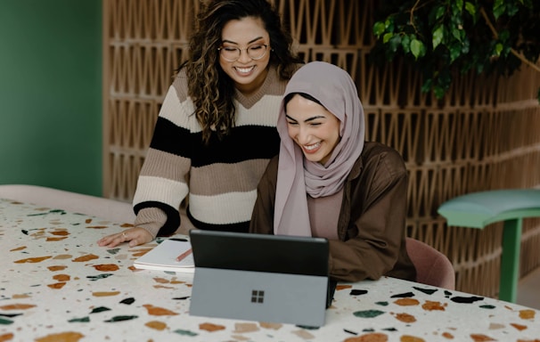 Two women sitting at a table with a laptop