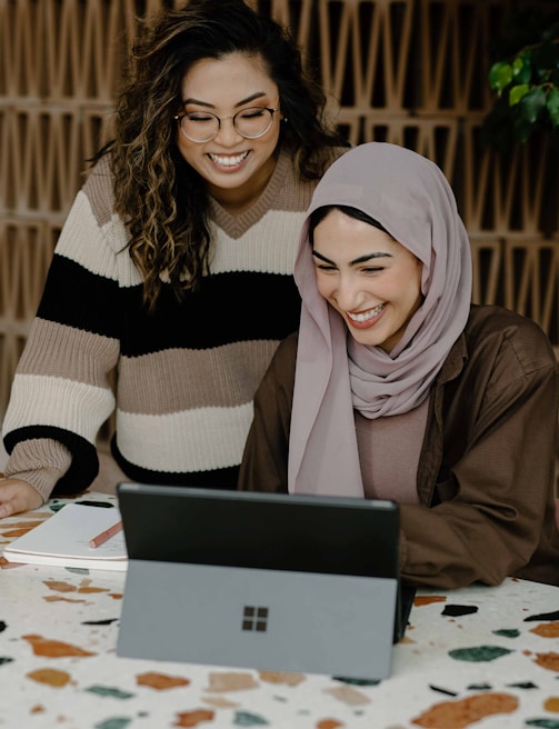 Two women sitting at a table with a laptop