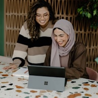 Two women sitting at a table with a laptop