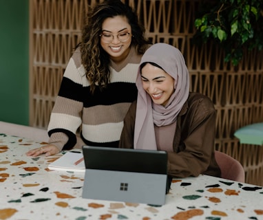 Two women sitting at a table with a laptop