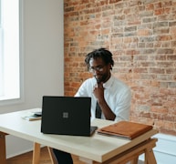 a man sitting at a table in front of a laptop