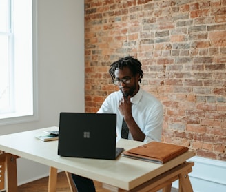 a man sitting at a table in front of a laptop