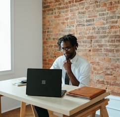 a man sitting at a table in front of a laptop