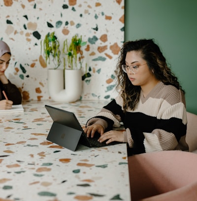 Two women setting at a table working