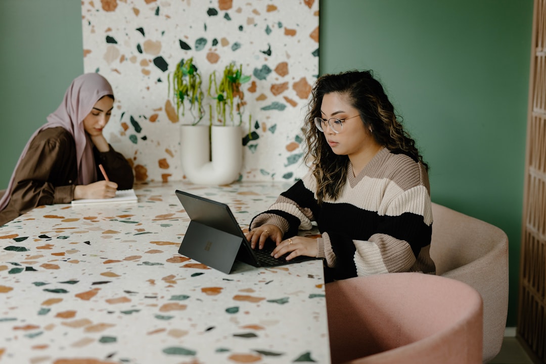 Two women setting at a table working,