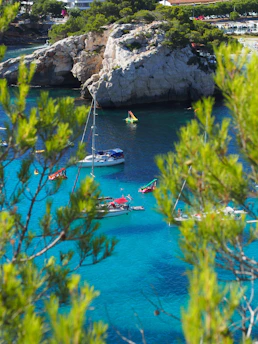 A serene coastal trail with hikers overlooking turquoise waters and a sailboat in the distance.