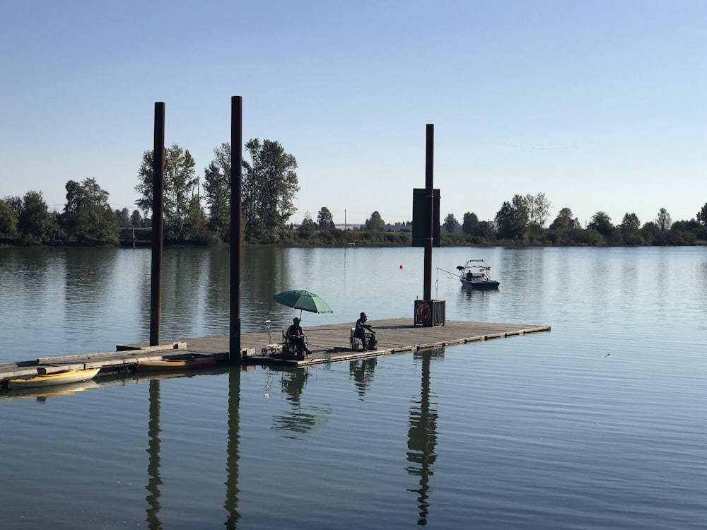 a couple of people on a dock with an umbrella