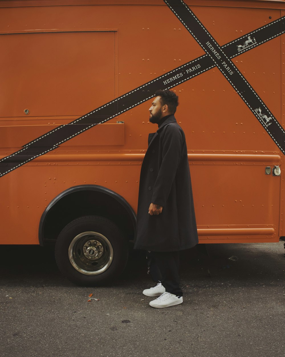 a person standing in front of a large orange truck