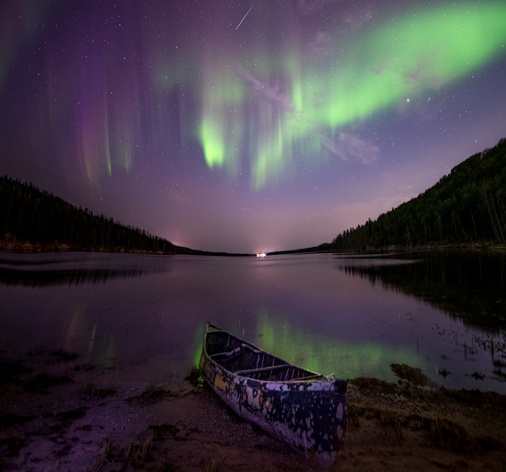um barco em um lago com luzes verdes no céu