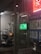 The scene depicts a store window at night with a green ATM sign. Inside, there's a black mobility scooter covered with transparent plastic and marked with a price tag. Surrounding signage includes references to THC, COVID-19 tests, and a lottery jackpot display.