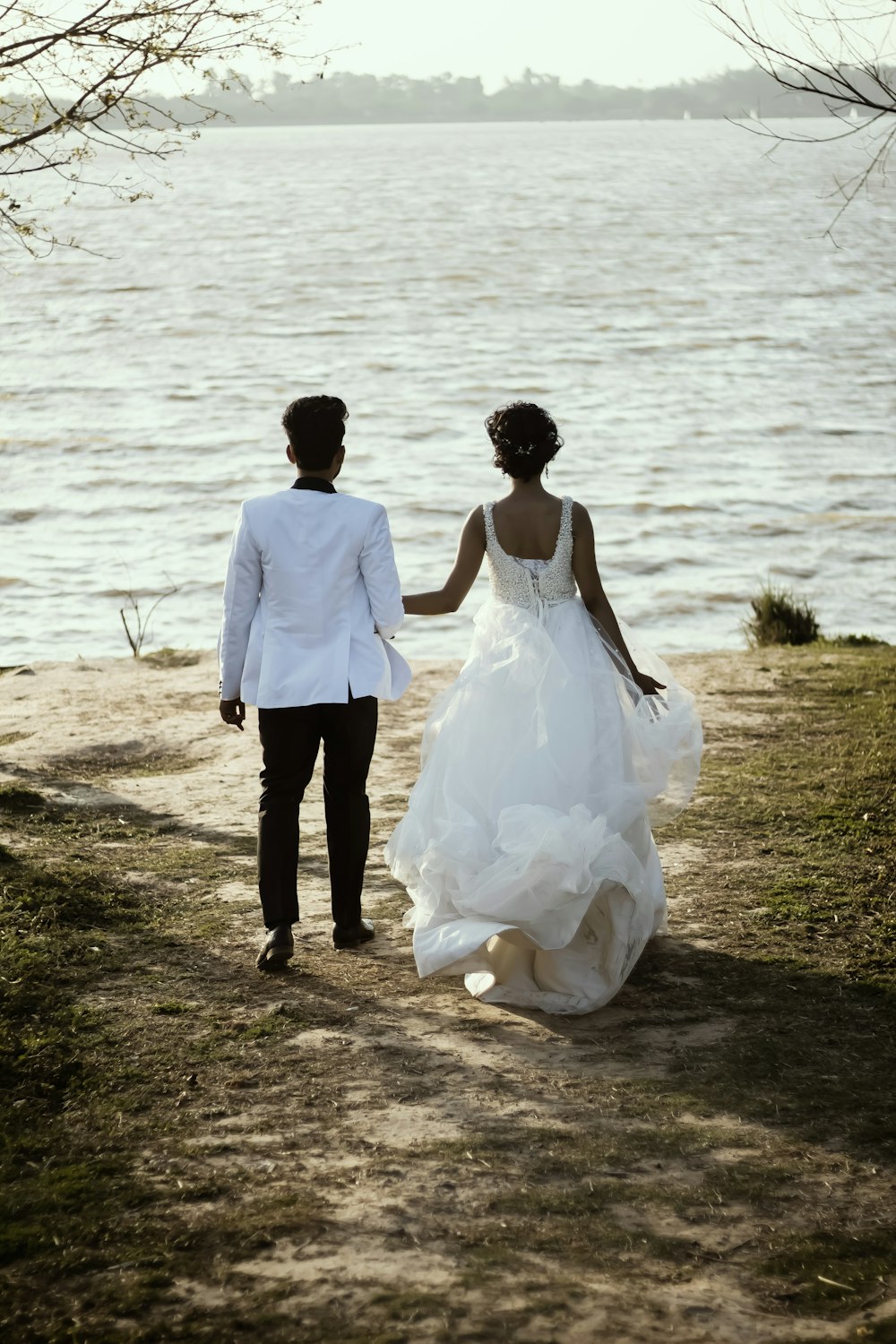 a man and woman walking down a path by a body of water