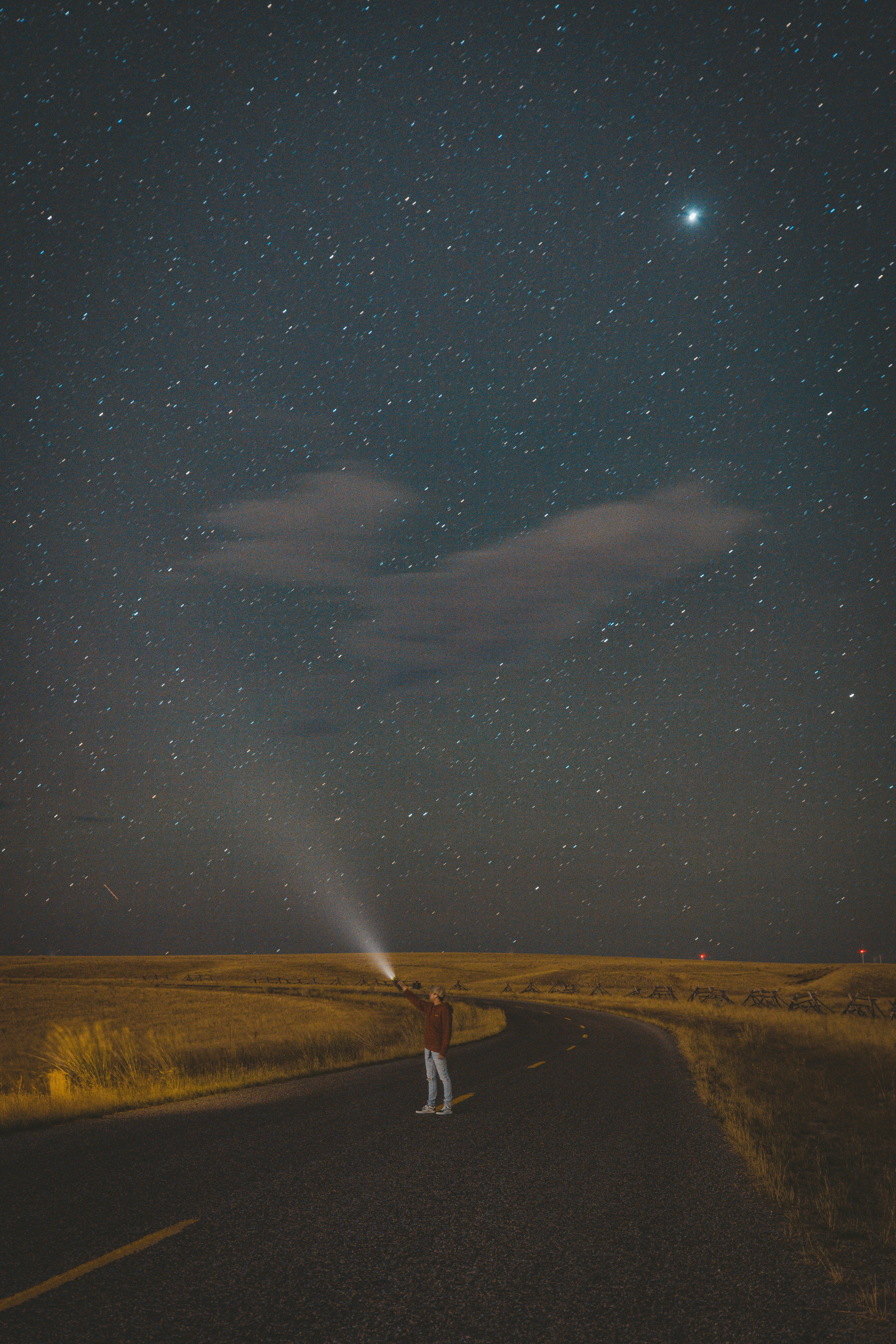 空に明るい光が差し込む道路に立っている人