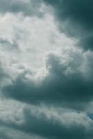 A sky filled with various fluffy and dense clouds, displaying different shades of gray and white. The clouds appear to be thick and the atmosphere is overcast, suggesting a moody or stormy weather condition.