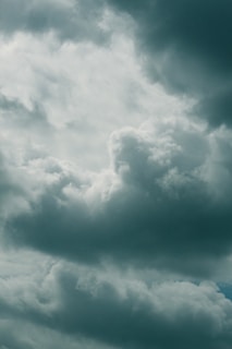 A sky filled with various fluffy and dense clouds, displaying different shades of gray and white. The clouds appear to be thick and the atmosphere is overcast, suggesting a moody or stormy weather condition.