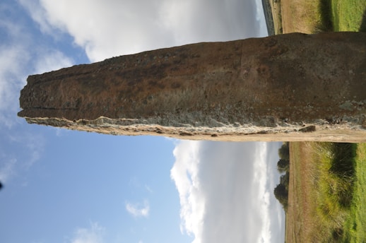 A weathered rune stone standing tall amidst a misty Nordic forest at dawn.