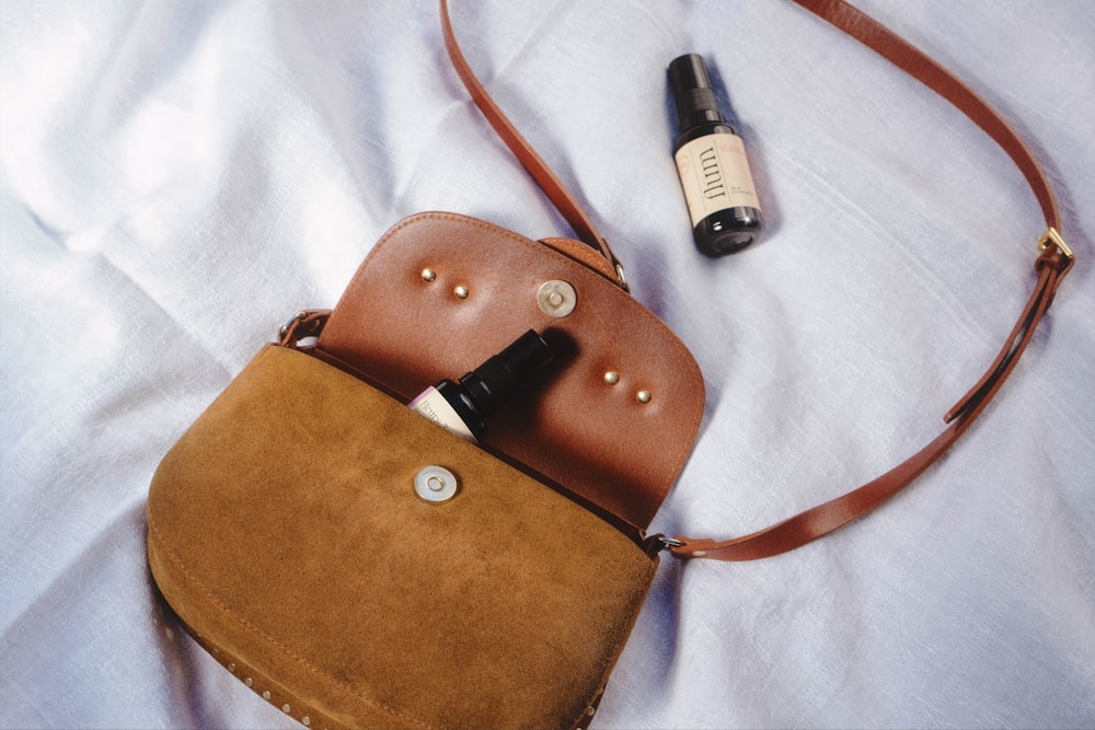 a brown leather purse with a black strap