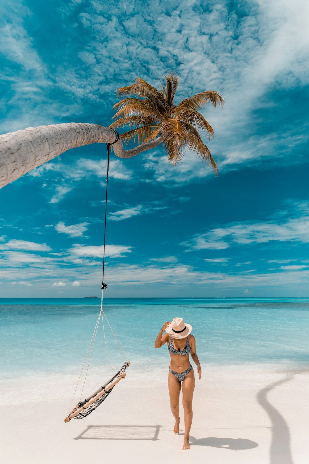 a person standing on a beach with a palm tree and a boat