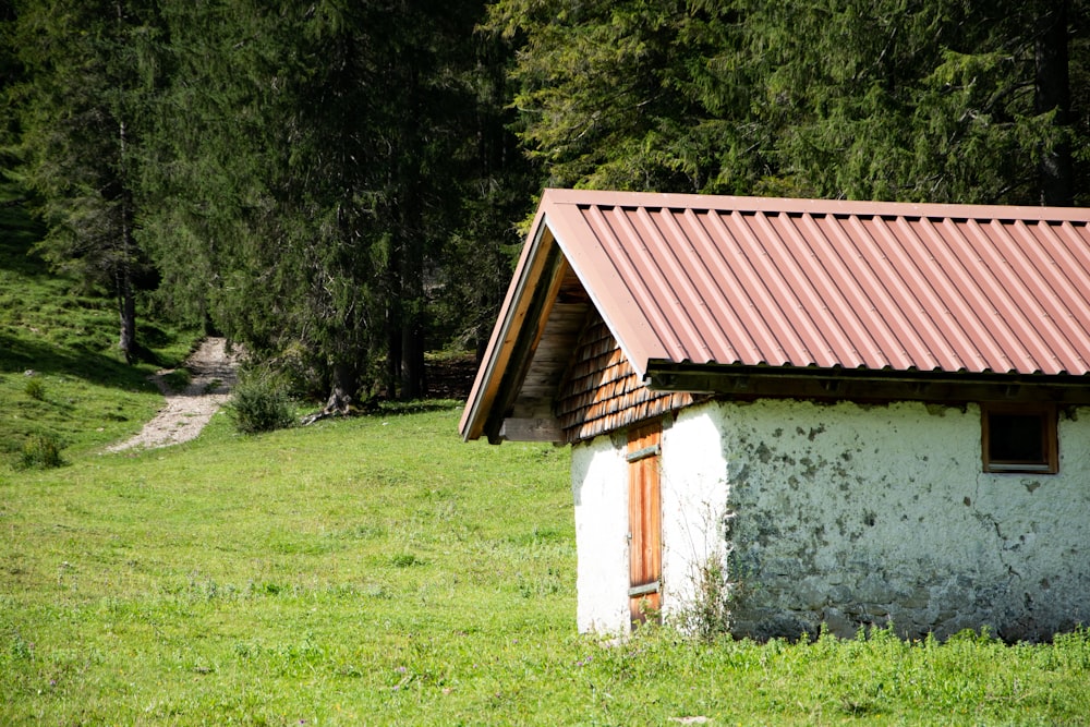 a small white building in a grassy area with trees in the background
