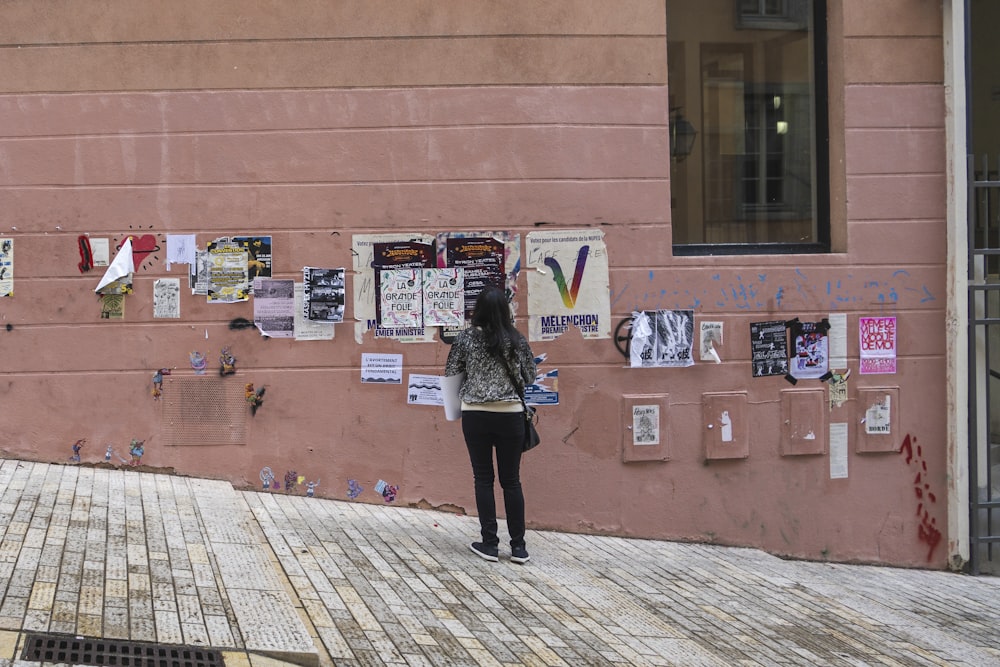 une personne debout devant un mur avec des affiches dessus