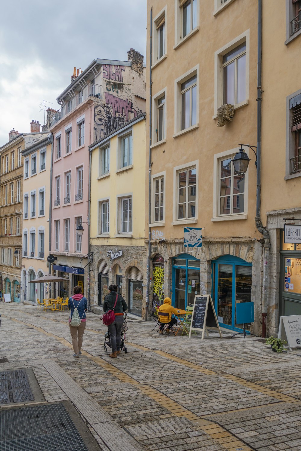 a group of people walking on a street between buildings