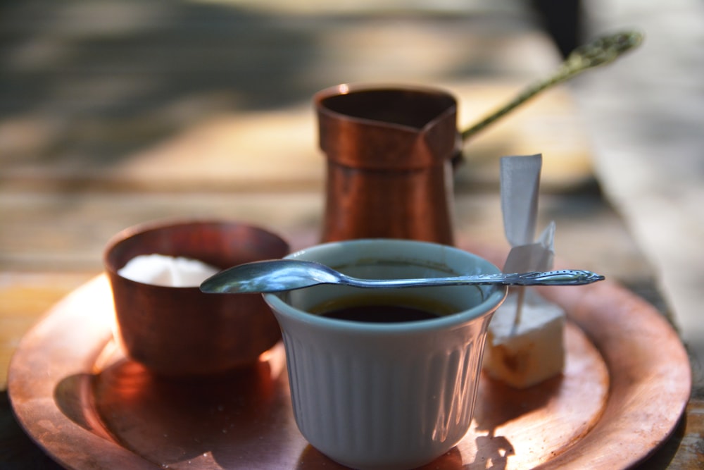 uma mão segurando uma colher sobre uma xícara de chá