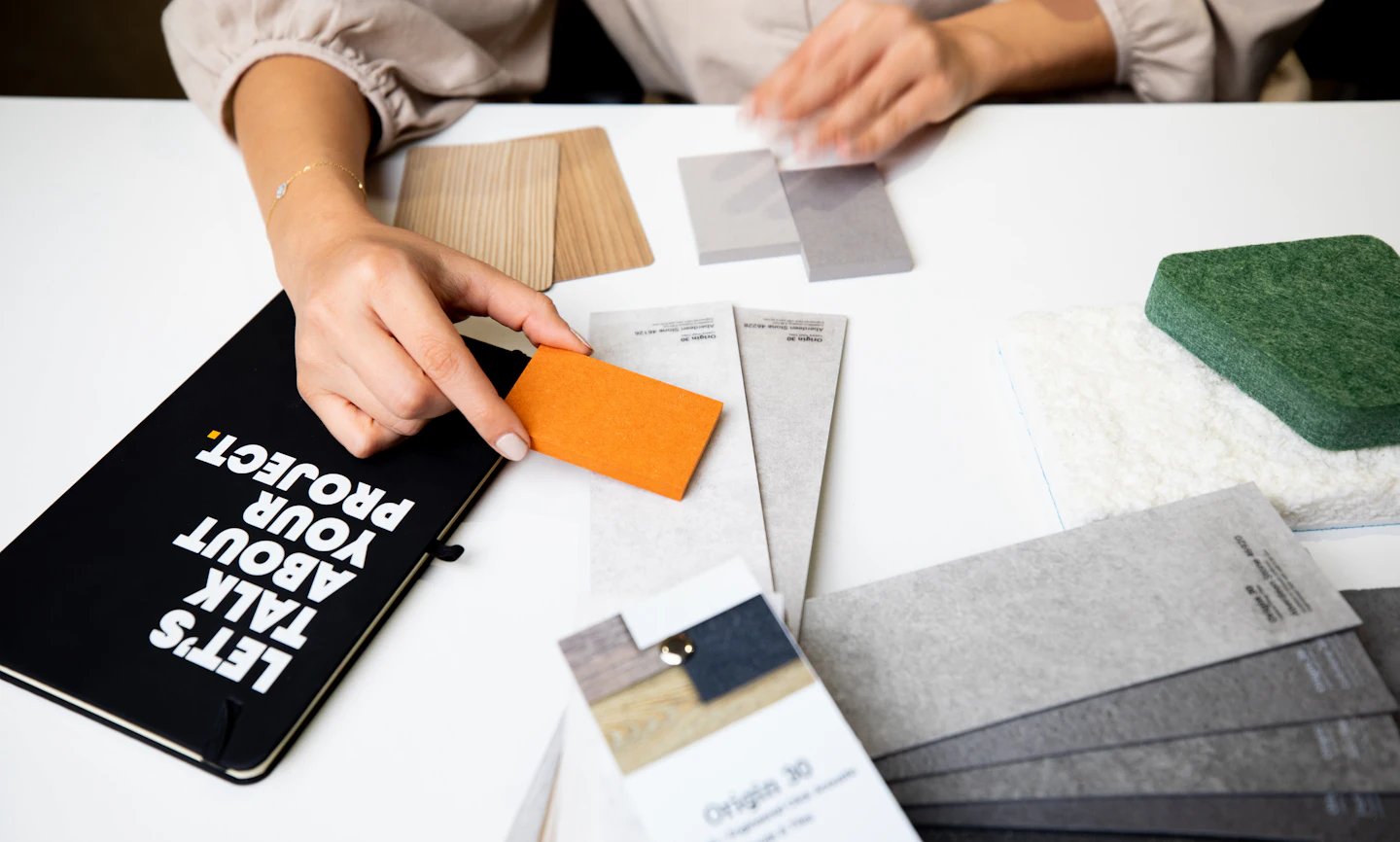 Material samples beside a notebook that reads “Let’s talk about your project”