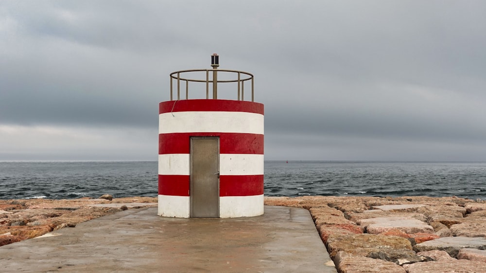 a red and white striped structure on a rocky beach