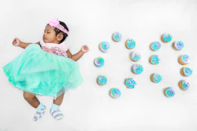 a baby girl in a green tutu and a bunch of cupcakes