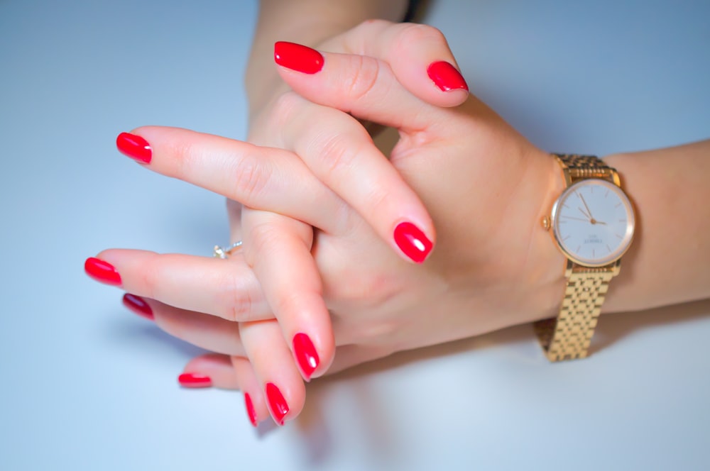a woman's hand with red fingernails and a watch